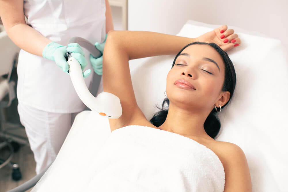 Woman on treatment bed getting laser hair removal on arm