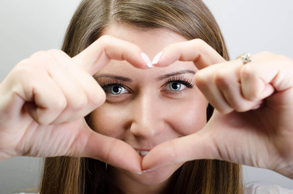 Woman with long lashes making a heart with her hands